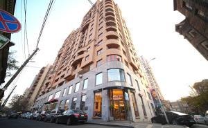 Un edificio alto con coches aparcados delante. en Studio apartments in the centre of Yerevan by Sweet Home, en Ereván