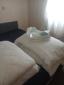 two white beds with a bag on top of them at Sunrise Caravan in Dymchurch