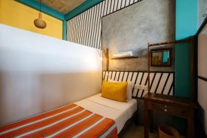 a small bedroom with a bed and a table at Dots Bay House in Hiriketiya
