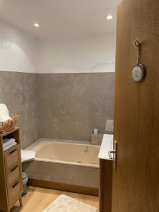 a bathroom with a tub and a clock on the wall at Chambres d'hôtes L'Ecrin des Saveurs in Schwenheim +44 photos