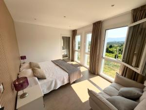 a bedroom with a bed and a couch and a large window at Casa Rural Abreu Do Louro in Arbo