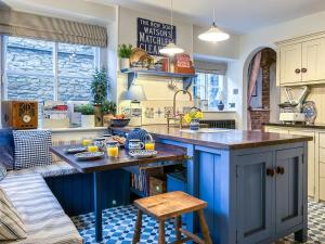 une cuisine avec des armoires bleues et un îlot bleu dans l'établissement Pantile Cottage, à Pickering