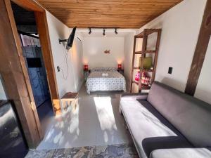 a bedroom with a bed and a couch in a room at Amorada do Rosa - 350m do Centrinho do Rosa in Praia do Rosa