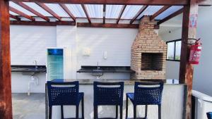 Una cocina con cuatro sillas y una chimenea de ladrillo. en Nawa Residence - Praia de Tamandaré, en Tamandaré