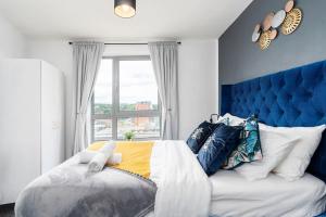 a bedroom with a large bed with a blue headboard and a window at Stylish 2BR Apartment near Sheffield City Centre in Sheffield