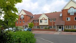 a large brick building with cars parked in a parking lot at Spacious Two Bedroom Apartment in Bracknell in Bracknell