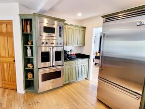 a kitchen with a stainless steel refrigerator and wooden floors at Large Estate Venue 2 hot tubs 2 treehouses in Snohomish