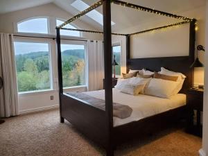 a bedroom with a canopy bed with a large window at Large Estate Venue 2 hot tubs 2 treehouses in Snohomish