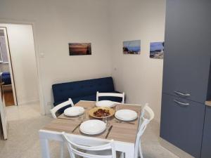 a dining room table with white chairs and a blue cabinet at Botticelli Sea Apartment in Trieste
