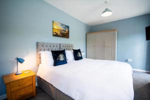 a bedroom with a large white bed with blue walls at Gamekeepers Cottage in Holyhead