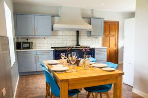 a kitchen with a wooden table and blue cabinets at Gamekeepers Cottage in Holyhead