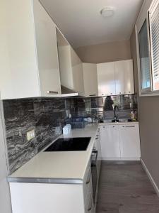 a small kitchen with white cabinets and a sink at Valentina Cozy 2-Bedroom House in Lushnjë