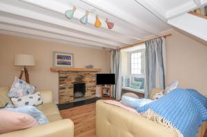een woonkamer met twee banken en een open haard bij 2 Porthilly Cottages in Wadebridge