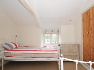 een witte slaapkamer met een bed en een raam bij 2 Porthilly Cottages in Wadebridge