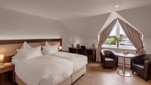 ein Hotelzimmer mit einem Bett und einem Tisch und Stühlen in der Unterkunft Der Romantik-Hof Greetsiel in Greetsiel + 37 Fotos