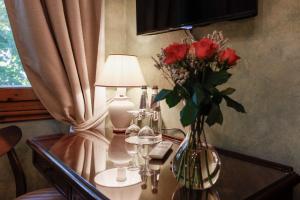 a vase of roses on a table with a lamp at Hotel Bellavista Impruneta in Impruneta