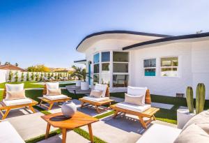 un patio con sillas y mesas frente a una casa en White Pearl - Pool - Spa - Mountain Views, en Palm Springs
