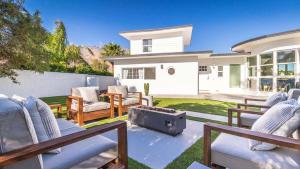 Un patio con sillas y una fogata frente a una casa. en White Pearl - Pool - Spa - Mountain Views, en Palm Springs