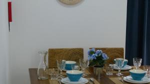 a wooden table with blue bowls and glasses on it at Watching Azores Apartment in Ponta Delgada