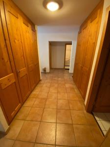 Un pasillo vacío con armarios de madera y suelo de baldosas. en Spacious and comfortable, en Val dʼIlliez