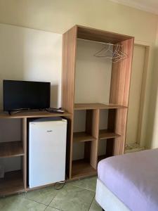 a room with a bed and a television and a small refrigerator at Residencial Refugio do Mar in Florianópolis