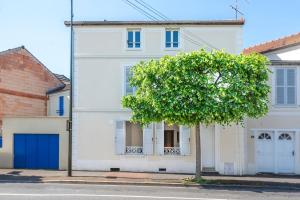 a white house with a tree in front of it at Le Nid Urbain - Center - Ground floor in Meaux