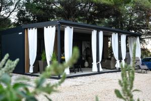 a black and white shed with white curtains at Mobile home Periska, Pakoštane in Pakoštane