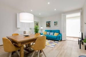 a living room with a table and a blue couch at Lovely Designed House Connected To Center in Cornellà de Llobregat