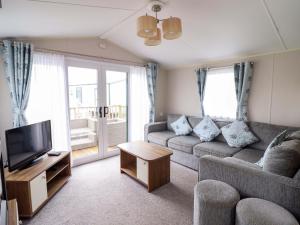 a living room with a couch and a tv at Sea Breeze C38 Dyffryn Seaside Estate in Dyffryn