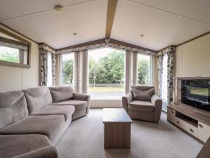 a living room with a couch and a tv at Beach Retreat E19 Dyffryn Seaside Estate in Dyffryn