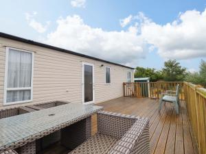 a wooden deck with a house and a chair at Beach Retreat E19 Dyffryn Seaside Estate in Dyffryn