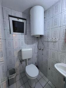 a bathroom with a toilet and a tv on the wall at Drenis Home in Prizren