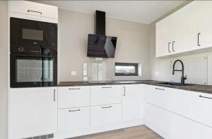 Una cocina con gabinetes blancos, un fregadero y un microondas. en Central No6, en Vestvågøya 8 fotos más