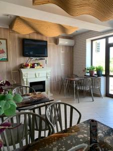 a living room with tables and chairs and a fireplace at RAZAM Hotel Bosteri in Bosteri