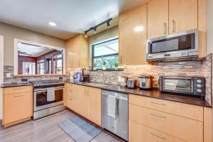 a large kitchen with wooden cabinets and stainless steel appliances at 1 Mi to UF Campus Group Retreat with Outdoor Oasis in Gainesville