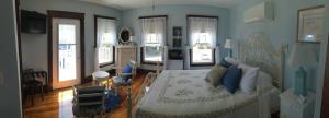 um quarto com uma cama grande com paredes e janelas azuis em The Rebekah Inn em Old Orchard Beach