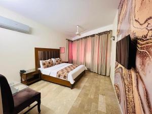 a bedroom with a bed and a chair in a room at Imperial Guest House DHA in Karachi +24 photos