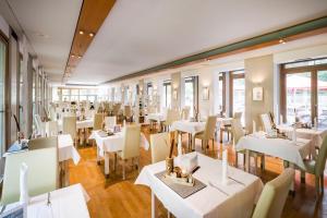 a restaurant with white tables and chairs and windows at Ringhotel Schorfheide I Waldresort Werbellinsee in Joachimsthal