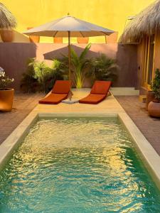 a pool with two orange chairs and an umbrella at Casa Moka in Puerto Escondido +13 photos