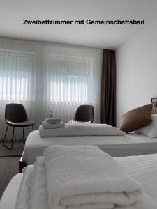 a hotel room with two beds and two chairs at Elha Hotel in Stuttgart