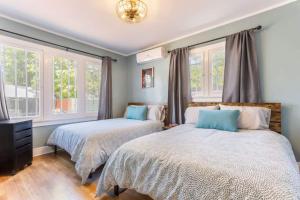 two beds in a room with two windows at Magnificent House Minutes From Hollywood in Los Angeles