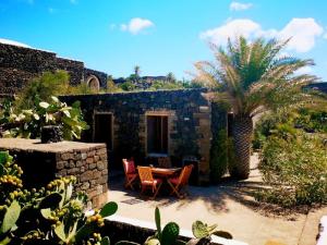een patio met een tafel en stoelen en een palmboom bij Dammusino A-mare in Pantelleria