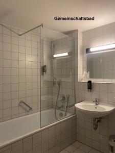 a bathroom with a tub shower and a sink at Elha Hotel in Stuttgart