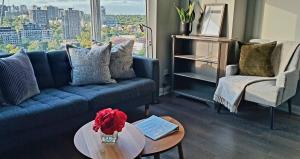a living room with a blue couch and a table at Yorkville's Premier 2-Bedroom, 2-Bath Suite in Toronto