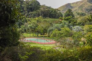 a tennis court in a park with trees and mountains at Spa Posse do Corpo in Araras Petropolis