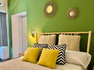 un lit avec deux miroirs sur un mur vert dans l'établissement Domus Rubra, à Castelsardo