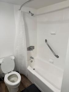 a white bathroom with a toilet and a bath tub at Cozy Studio in Houston +14 photos