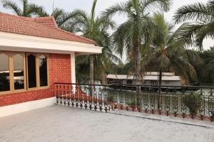 a house with a fence next to a house with palm trees at Mansion Du Lac kumarakom in Kumarakom