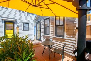 a patio with a table and chairs under a yellow umbrella at Walk to Beach Shopping and Dining in Provincetown