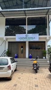 a motorcycle parked in front of a building with a car at Lowfare Hotels Medical College in Kozhikode